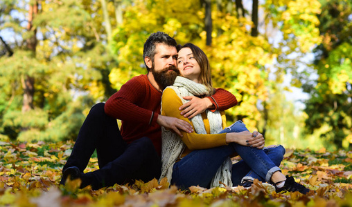 夫妇在爱与围巾坐在叶子在公园