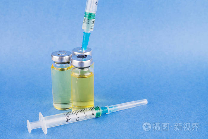 在蓝桌上注射药物和穿刺注射器的瓶子.水平组合