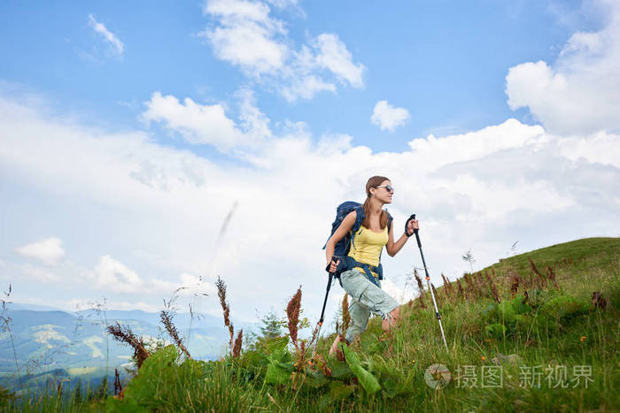 迷人的女子旅游徒步登山小径 走在草地上 穿着背包和太阳镜 使用