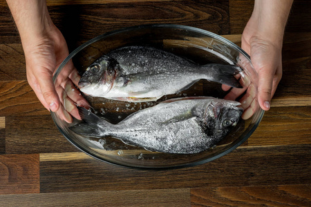 厨师烹调海鱼与调味料在木桌上