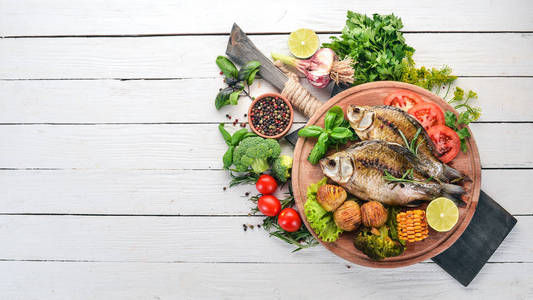 烤鱼配香料和蔬菜。在木质的背景鲤鱼。顶部视图。复制空间