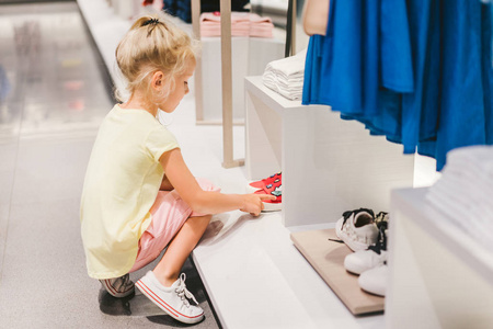 可爱的小孩在商店里选择鞋子的侧面视图