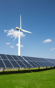 风力发电机的电力从三叶片和太阳能电池板的光电的背景下的云和蓝色的天空绿草