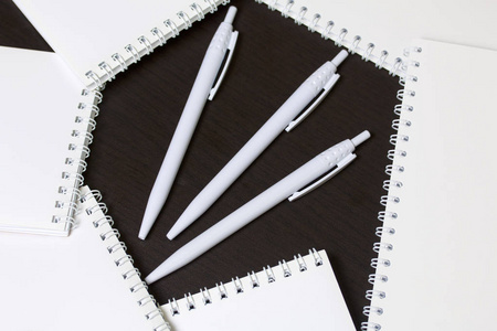 用于笔记和草图的白色弹簧垫和圆珠笔。学校和教学文具。在黑暗背景下