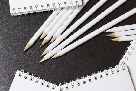 白色的弹簧垫和简单的铅笔, 用于笔记和草图。学校和教学文具。在黑暗背景下