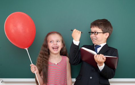 男孩和女孩带着气球在黑板背景上