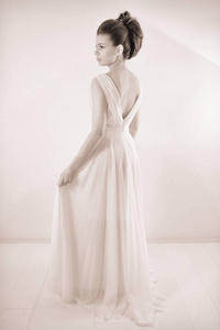 黑白工作室拍摄的典雅的女人与经典的发型摆在漂亮的白色礼服