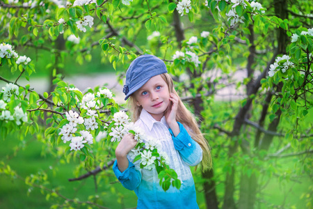 小女孩在绽放春日的苹果园树的画像