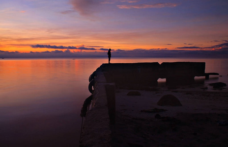 美丽的日出与人的剪影从远方。早晨平静的海水