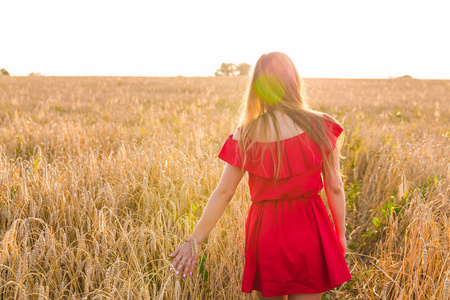 年轻女子走在麦田与背景上的太阳