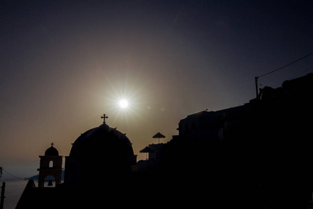 浪漫日落剪影场面, 圣托里尼, 希腊。日落前不久, 教堂在前面。这个旅游目的地岛的典型建筑。太阳射线衍射