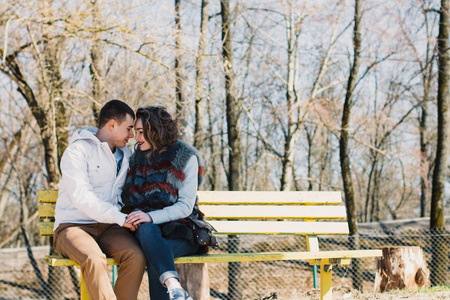幸福夫妻爱拥抱和分享情感，牵着手在河边的长椅上