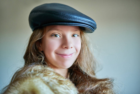 小小女孩微笑着在温暖的毛皮大衣戴着黑色帽子