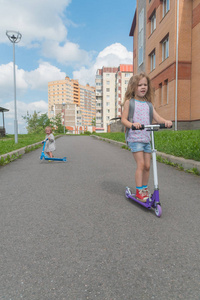 阳光明媚的夏日, 一个女孩和一个孩子在滑板车上
