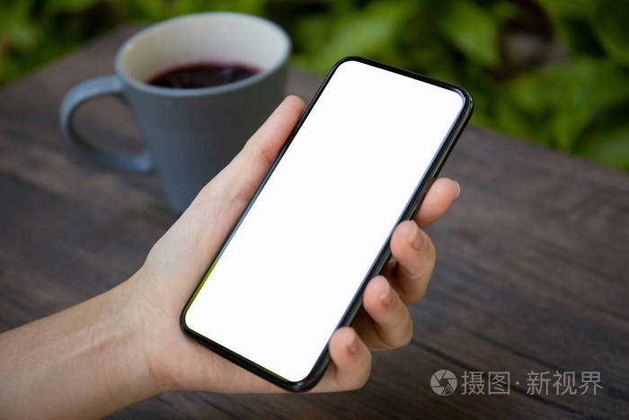 手持手机的女性手放在桌子上的隔离屏幕上