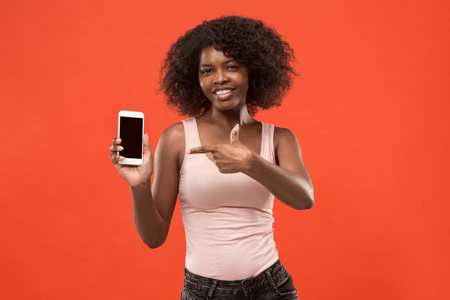 一个充满自信的偶然的非洲女孩的肖像显示空白屏幕手机在红色背景下隔离