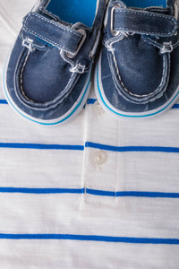 白色条纹的马球背景上的蓝色小船鞋。男孩的衣服。顶视图