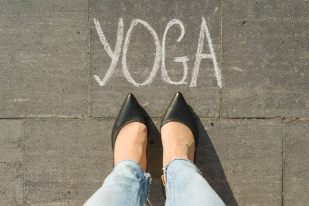 从上面看, 女性脚与文本瑜伽写在灰色人行道上