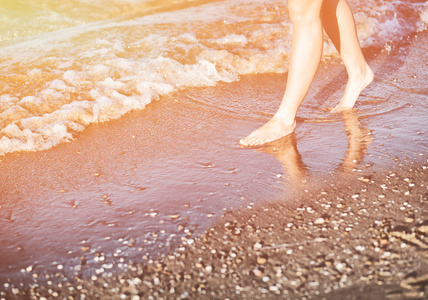 女人走在夏日的阳光，在沙滩上享受假期