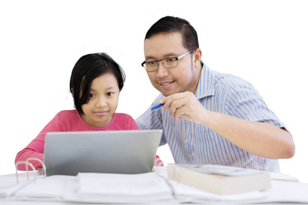 年轻父亲的肖像帮助他的女儿使用笔记本电脑, 而坐在演播室, 孤立的白色背景