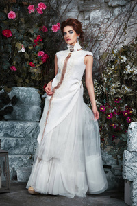 新娘在白色礼服与玫瑰在庭院里缠绕