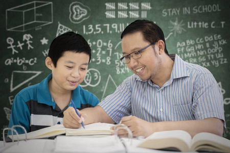 青春期男孩学生在课堂上学习与老师阅读的图片