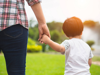 母女牵着手在公园里散步。孩子和妈妈的家庭概念