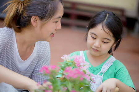 和她妈妈一起种植花卉的亚洲小孩