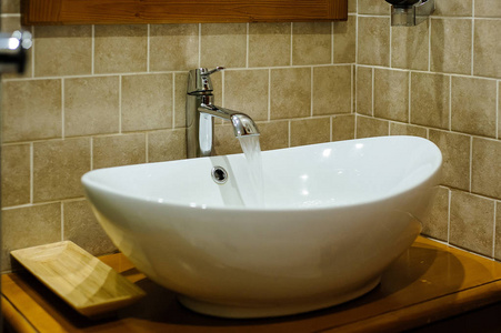 浴缸里的陶瓷脸盆, 水龙头里流淌着水。