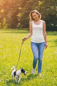 美丽的女人喜欢与她可爱的狗杰克罗素梗散步的性质。图像是故意色调