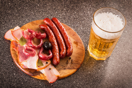 木板上的熏肉小吃和一杯淡啤酒图片