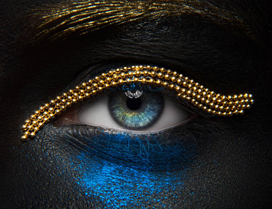 宏观和特写创意化妆主题 美丽的女性眼睛黑皮肤与金链和蓝色颜料