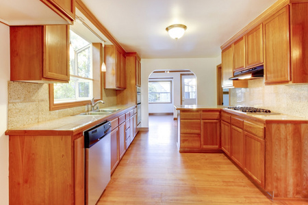 阳光明媚的棕色厨房内部与硬木地板和白色 ceili