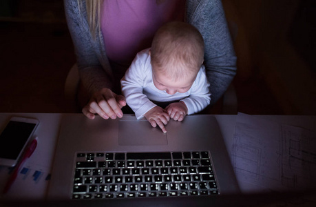 不可识别的母亲和儿子在膝上，笔记本电脑上工作