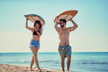 带着微笑的年轻夫妇在沙滩上漫步, 在暑假里玩得很开心。极限运动