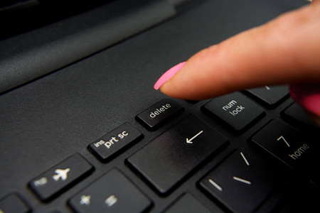 女性手指按下删除按钮黑色笔记本电脑