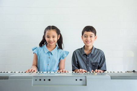 两个亚洲儿童在音乐学校玩音乐键盘