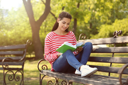美丽的年轻妇女在公园里休息与书