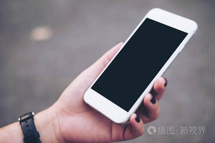 样机的手拿着白色手机空白的黑色屏幕,用于图像的模糊