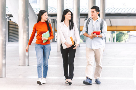 一组学生在大学户外拿笔记本电脑。教育理念