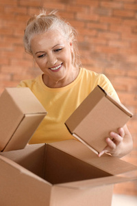 成熟的妇女与移动的箱子在新的家