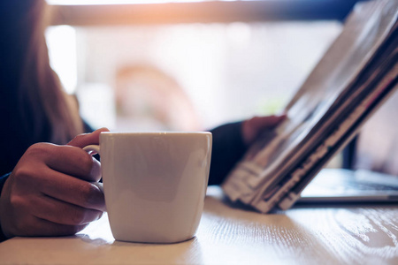 一个女商人读报纸，控股和在办公室在早上喝咖啡