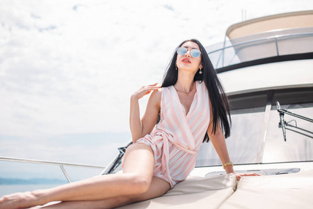 有吸引力的女人在游艇上晒黑, 享受阳光, 摆在甲板上的帆船