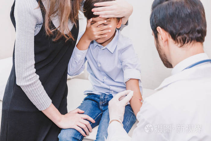 医生在医院的医生桌上给孩子和妈妈注射防护手套. 医疗保健
