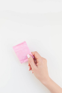 女子手用粉彩指甲抛光持有粉红色的每日卫生巾在白色背景与复制空间隔离。模板为女性美女博客社交媒体。女性保健理念
