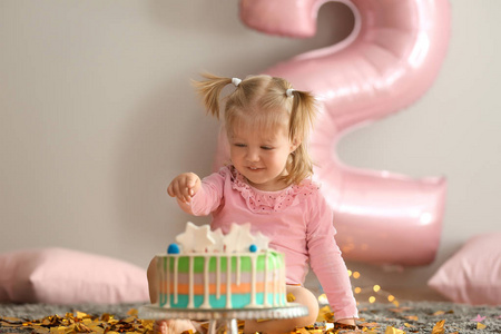 可爱的小女孩与美味的蛋糕坐在地毯上装饰的生日聚会