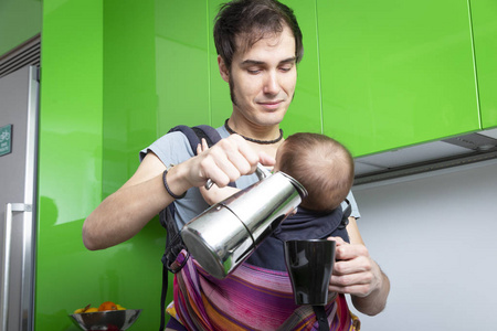 年轻的父亲与他的孩子在绿色现代厨房的载体上做咖啡