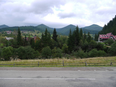 村庄的道路之间的群山环绕着绿树密布的天空下。休息, 旅游, 野餐的地方