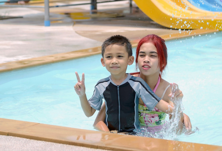 亚洲男孩和女孩坐在游泳池