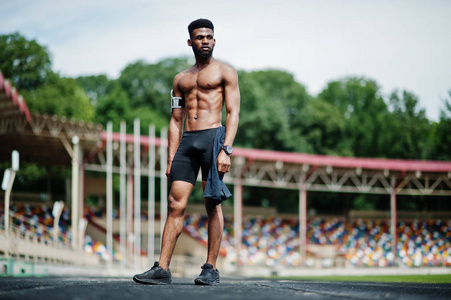 非洲裔美国人男性运动员运动裸躯干男子与运行运动手臂的情况下, 在体育场提出的手机, 摆在